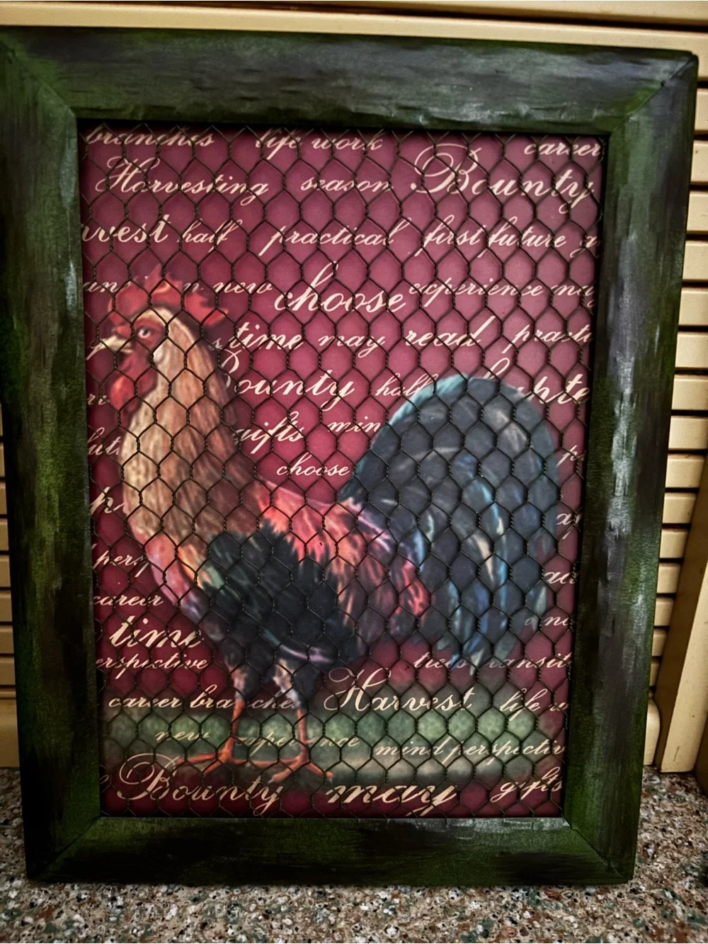 Rooster a rustic framed wall art piece behind chicken wire mesh.